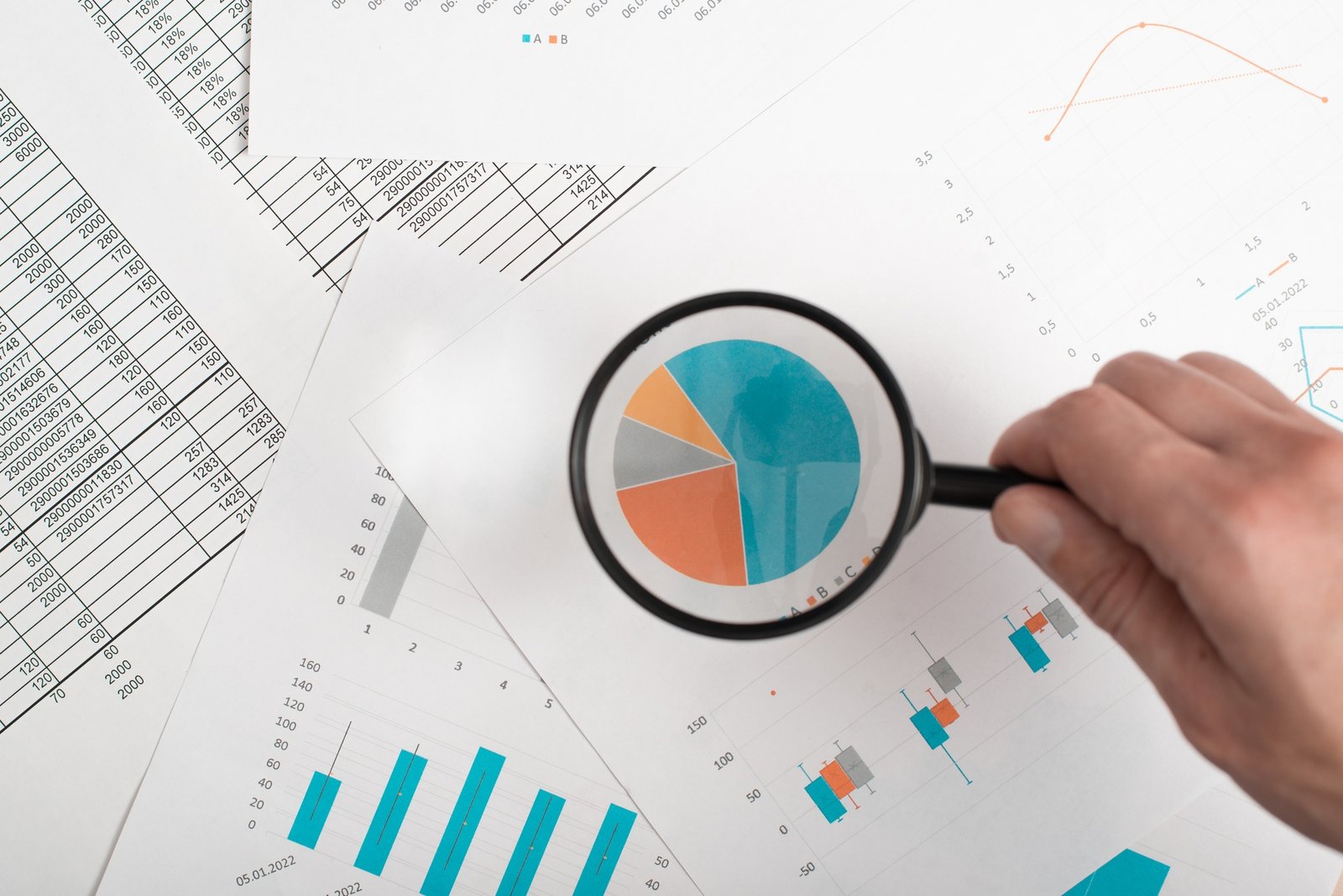Finance analytics, research of economic indicators concept. Close-up of hand holding magnifying
